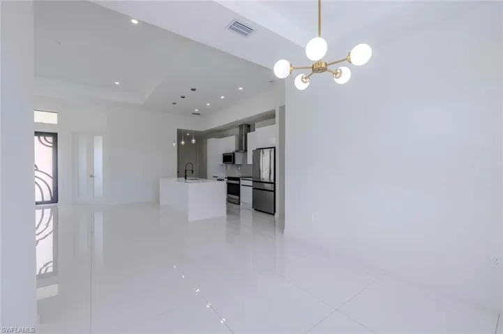 Unfurnished living room with visible vents, a raised ceiling, a chandelier, a sink, and light tile patterned floors