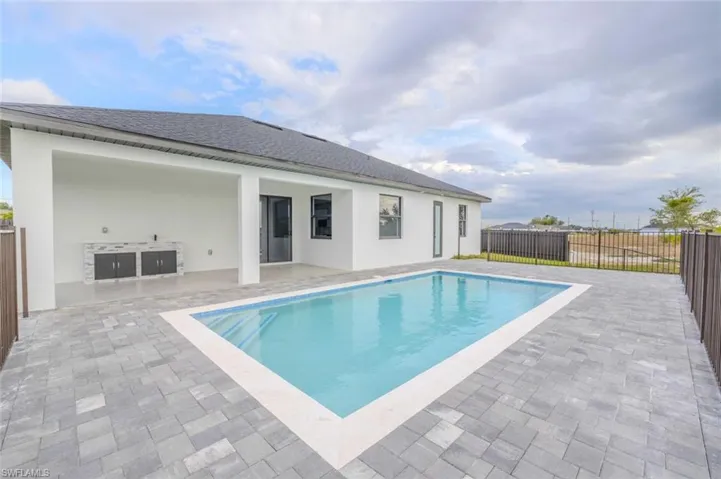 View of pool with fence, exterior kitchen, a fenced in pool, and a patio area