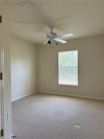 Carpeted empty room featuring baseboards, a ceiling fan, visible vents, and a textured ceiling