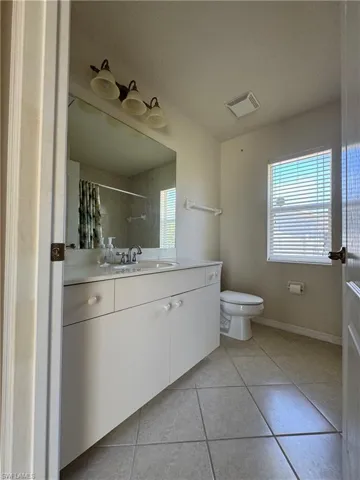 Bathroom with tile patterned floors, vanity, baseboards, toilet, and visible vents