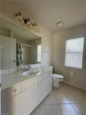 Full bath with toilet, vanity, baseboards, tile patterned flooring, and visible vents