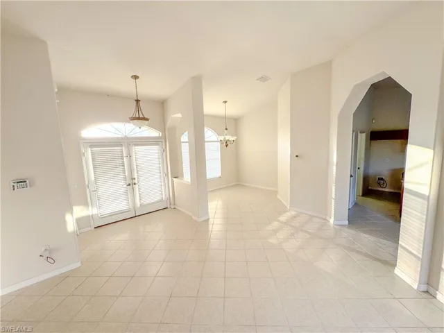 Entryway with french doors, baseboards, arched walkways, and light tile patterned floors