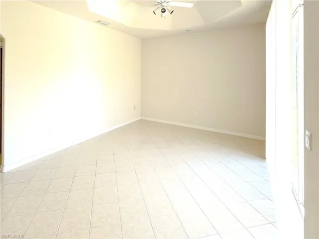 Spare room featuring baseboards, a ceiling fan, visible vents, and light tile patterned floors