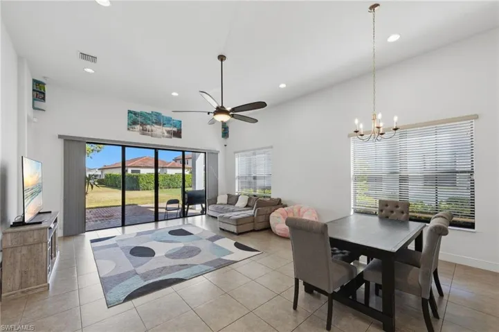 Dining room with a ceiling fan, a high ceiling, hanging lights, and light tile patterned floors