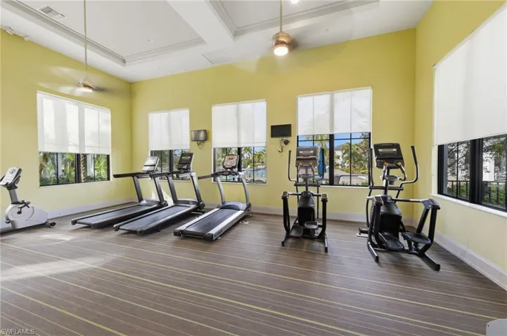 Exercise room with ceiling fan and coffered ceiling