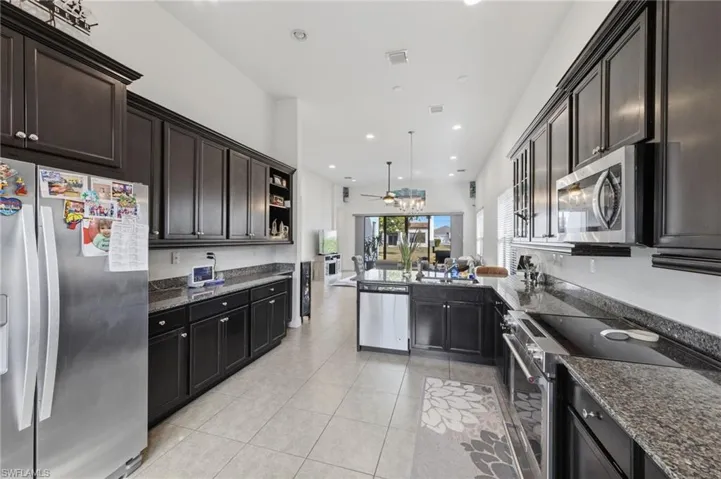 Kitchen featuring stainless steel appliances, dark stone counters, open shelves, a ceiling fan, and recessed lighting