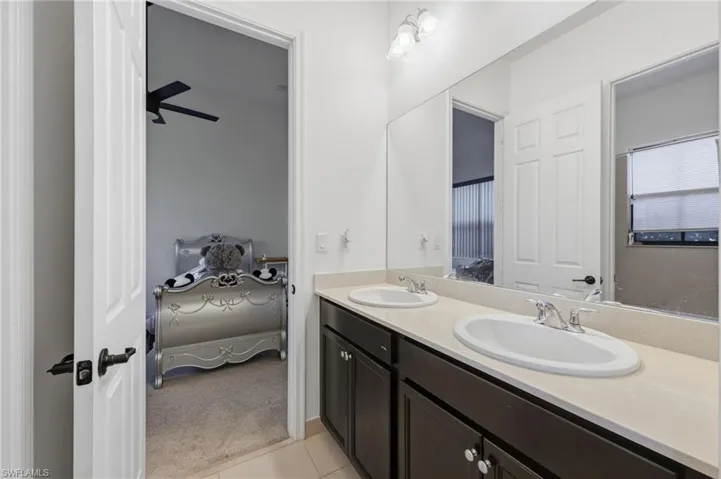 Bathroom featuring ensuite bath, double vanity, light carpet, ceiling fan, and light tile patterned flooring