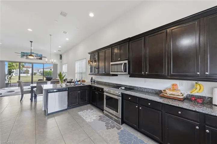 Kitchen featuring stainless steel appliances, dark stone countertops, ceiling fan, and a peninsula