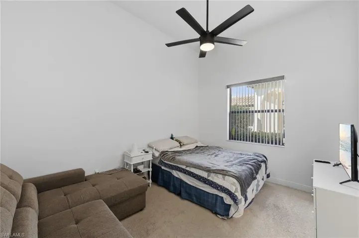Bedroom featuring light colored carpet, vaulted ceiling, and a ceiling fan