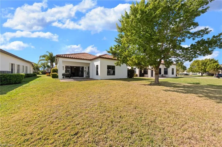 Back of house featuring stucco siding, a yard, a tile roof, and a patio area