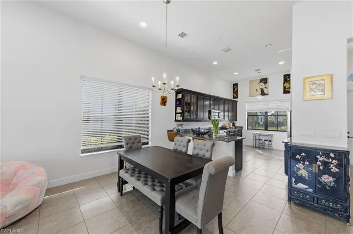 Dining room featuring light tile patterned floors, suspended lighting, and a high ceiling