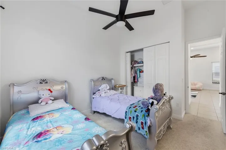 Carpeted bedroom with a high ceiling, a closet, and a ceiling fan