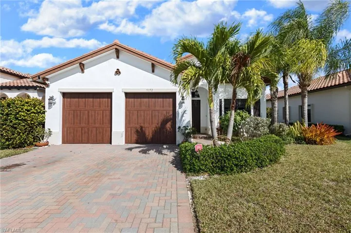 Mediterranean / spanish-style house with stucco siding, decorative driveway, a front yard, and a garage