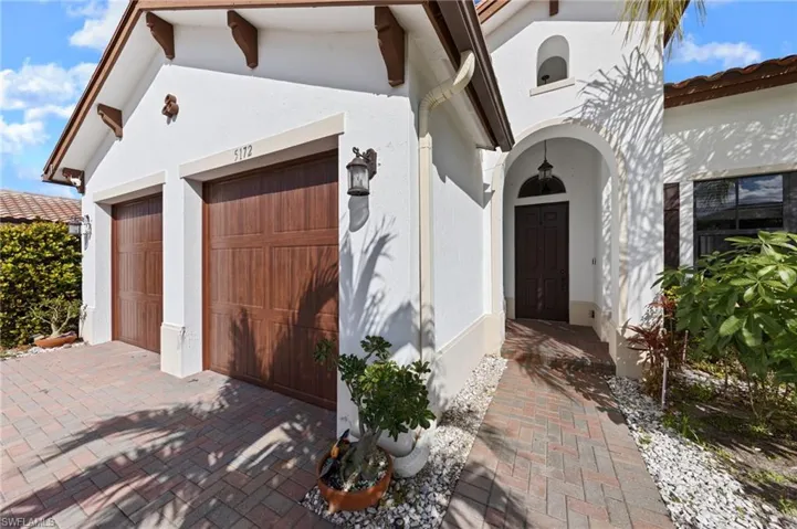 View of exterior entry featuring stucco siding, a garage, and decorative driveway