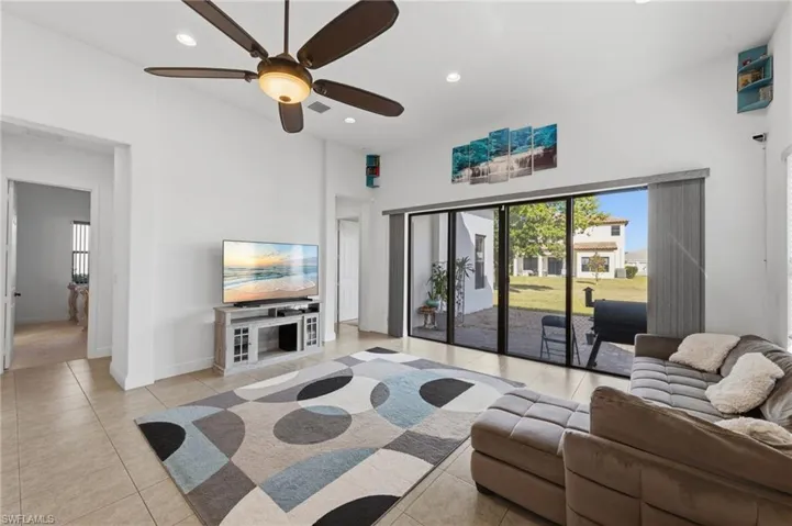 Living room featuring recessed lighting, a ceiling fan, light tile patterned floors, and a high ceiling