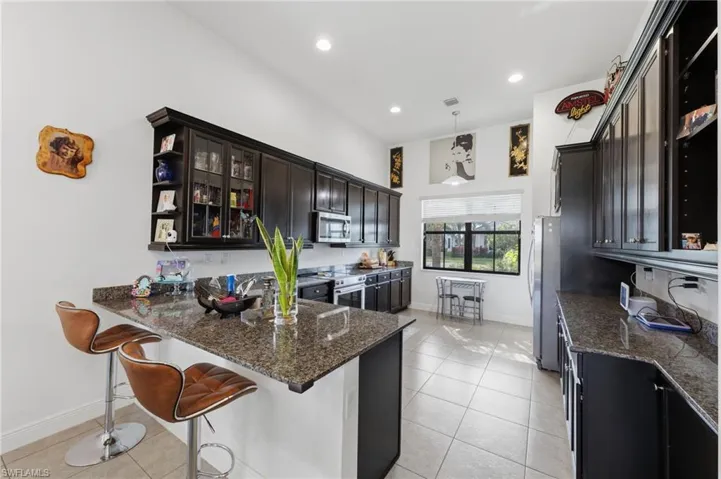 Kitchen featuring open shelves, dark stone countertops, a peninsula, and light tile patterned flooring