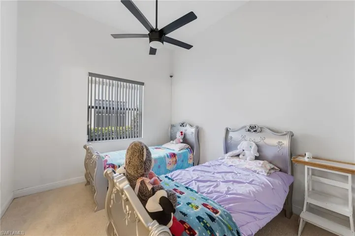 Bedroom featuring vaulted ceiling, light carpet, and a ceiling fan