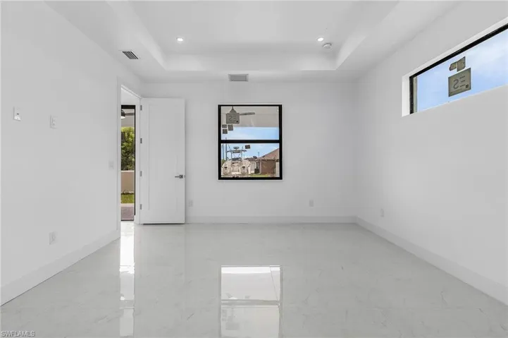 Empty room featuring a raised ceiling and a healthy amount of sunlight