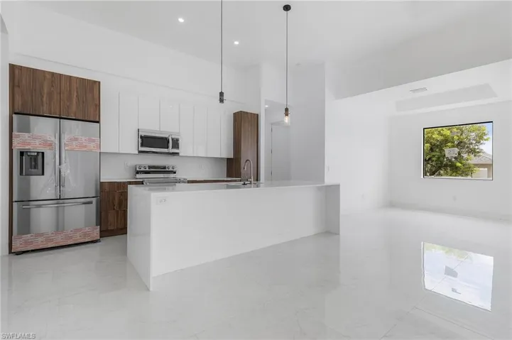 Kitchen featuring pendant lighting, sink, an island with sink, white cabinetry, and appliances with stainless steel finishes