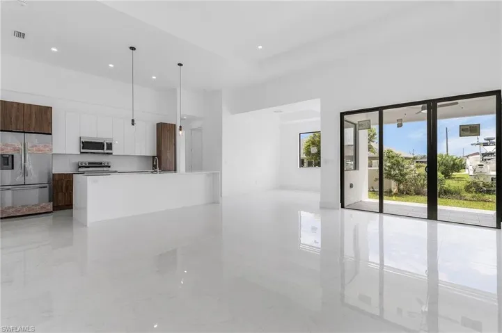 Kitchen featuring appliances with stainless steel finishes, an island with sink, white cabinets, pendant lighting, and sink