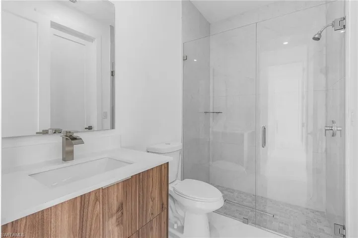 Bathroom with vanity, toilet, and a shower with door