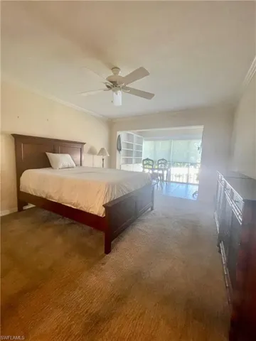 Carpeted bedroom featuring ceiling fan and crown molding