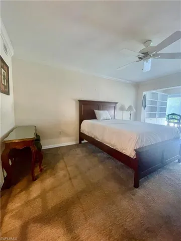 Bedroom with crown molding, ceiling fan, and dark carpet