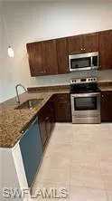 Kitchen featuring stainless steel appliances, dark wood finish cabinets, a peninsula, and light tile patterned flooring