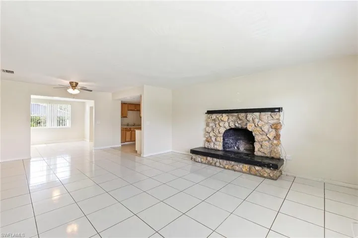 Unfurnished living room featuring light tile patterned floors, ceiling fan, and a fireplace