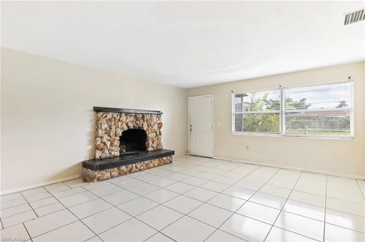 Unfurnished living room with light tile patterned flooring and a fireplace