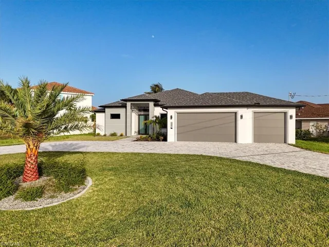Prairie-style house featuring decorative driveway, an attached garage, a front lawn, and stucco siding