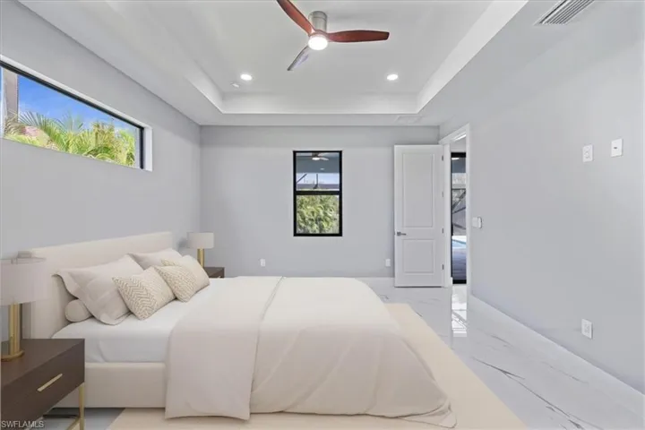 Bedroom featuring marble tiled flooring, multiple windows, recessed lighting, a raised ceiling, and ceiling fan