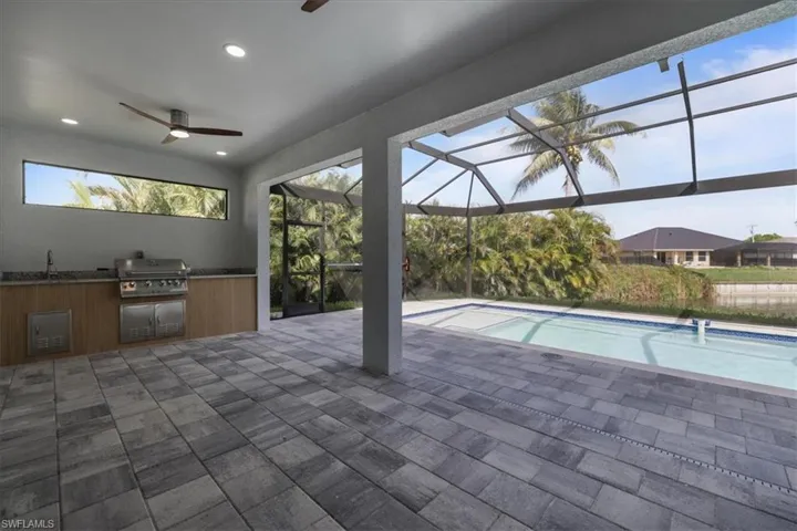 Outdoor pool featuring area for grilling, ceiling fan, a patio area, and a lanai