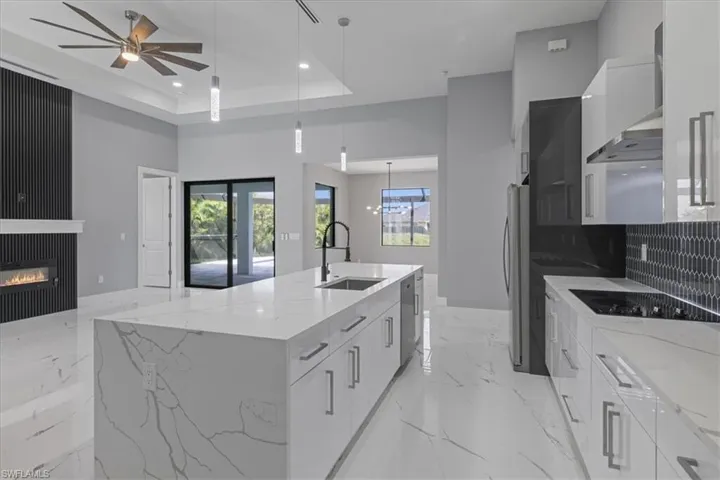 Kitchen with modern cabinets, a spacious island, white cabinets, recessed lighting, and a high ceiling