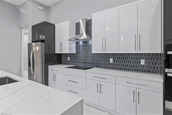 Kitchen featuring stainless steel fridge with ice dispenser, wall chimney range hood, and modern cabinets