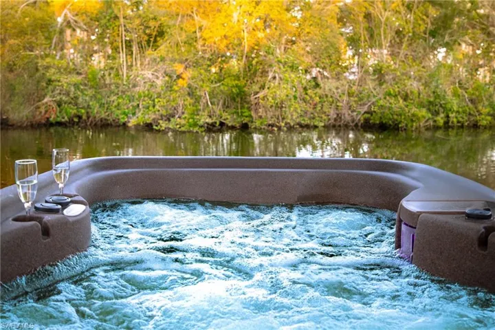 View of swimming pool with a hot tub and a water view