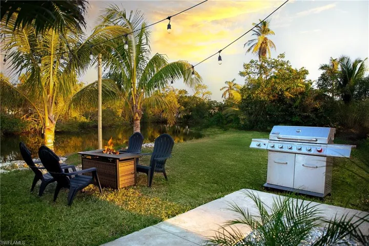 View of grassy yard featuring a fire pit and a patio