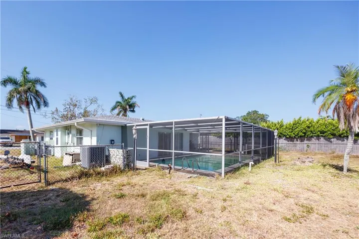 Back of property with a lawn, a gate, central air condition unit, a fenced in pool, and a fenced backyard