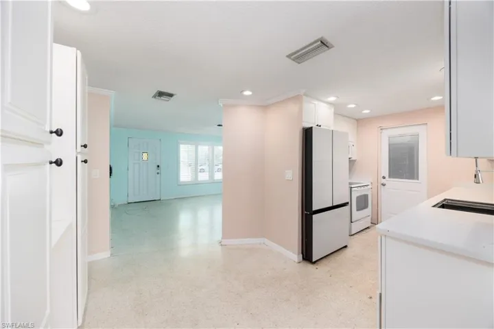 Kitchen with baseboards, light countertops, visible vents, and white appliances