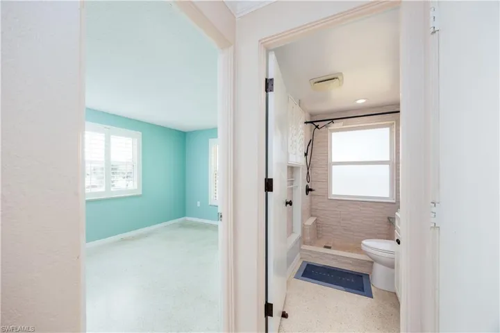 Full bath with plenty of natural light, a stall shower, and toilet
