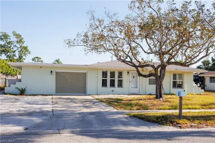 Ranch-style home featuring a garage, driveway, and stucco siding