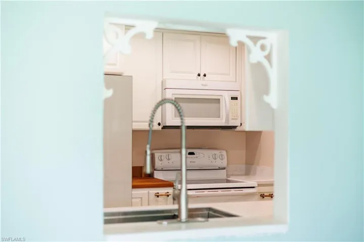 Kitchen featuring light countertops, white cabinets, and white appliances