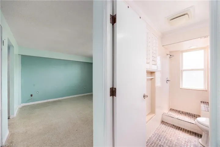 Full bathroom featuring toilet, visible vents, ornamental molding, and a stall shower
