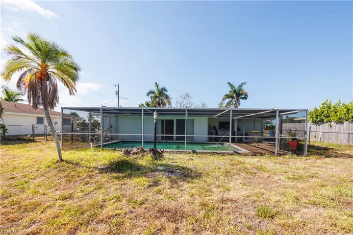 Back of house with a fenced in pool, a fenced backyard, a lanai, and a yard
