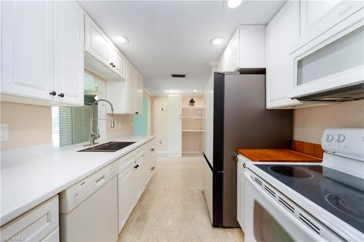 Kitchen with white appliances, recessed lighting, white cabinets, and a sink