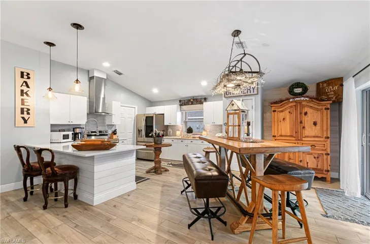 Kitchen with vaulted ceiling, a peninsula, white cabinets, stainless steel appliances, and a kitchen breakfast bar