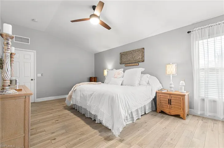 Bedroom with vaulted ceiling, light wood-style flooring, and a ceiling fan