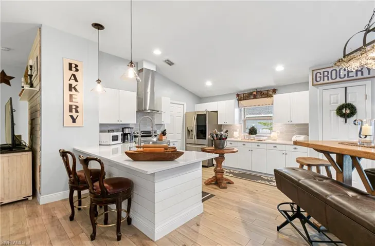 Kitchen featuring a peninsula, lofted ceiling, pendant lighting, tasteful backsplash, and a breakfast bar