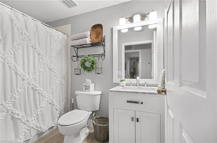 Full bathroom with a shower with shower curtain, vanity, and wood finished floors