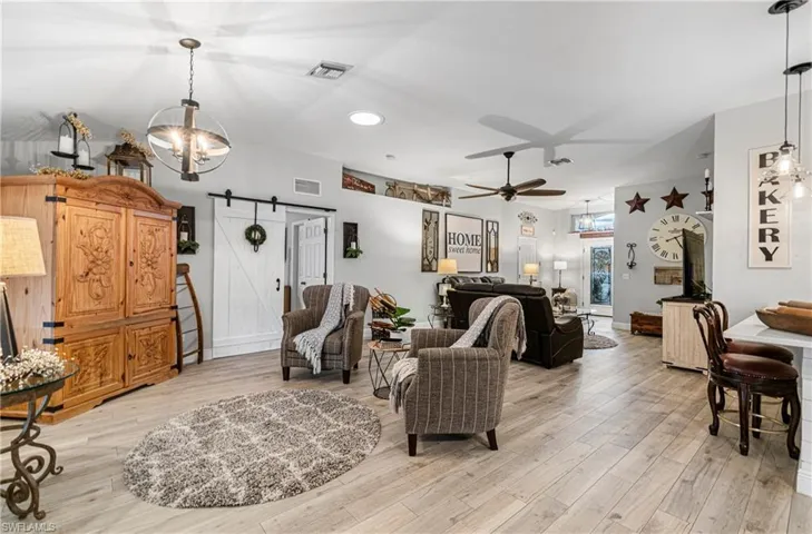 Living room featuring a barn door, a chandelier, light wood finished floors, recessed lighting, and a ceiling fan